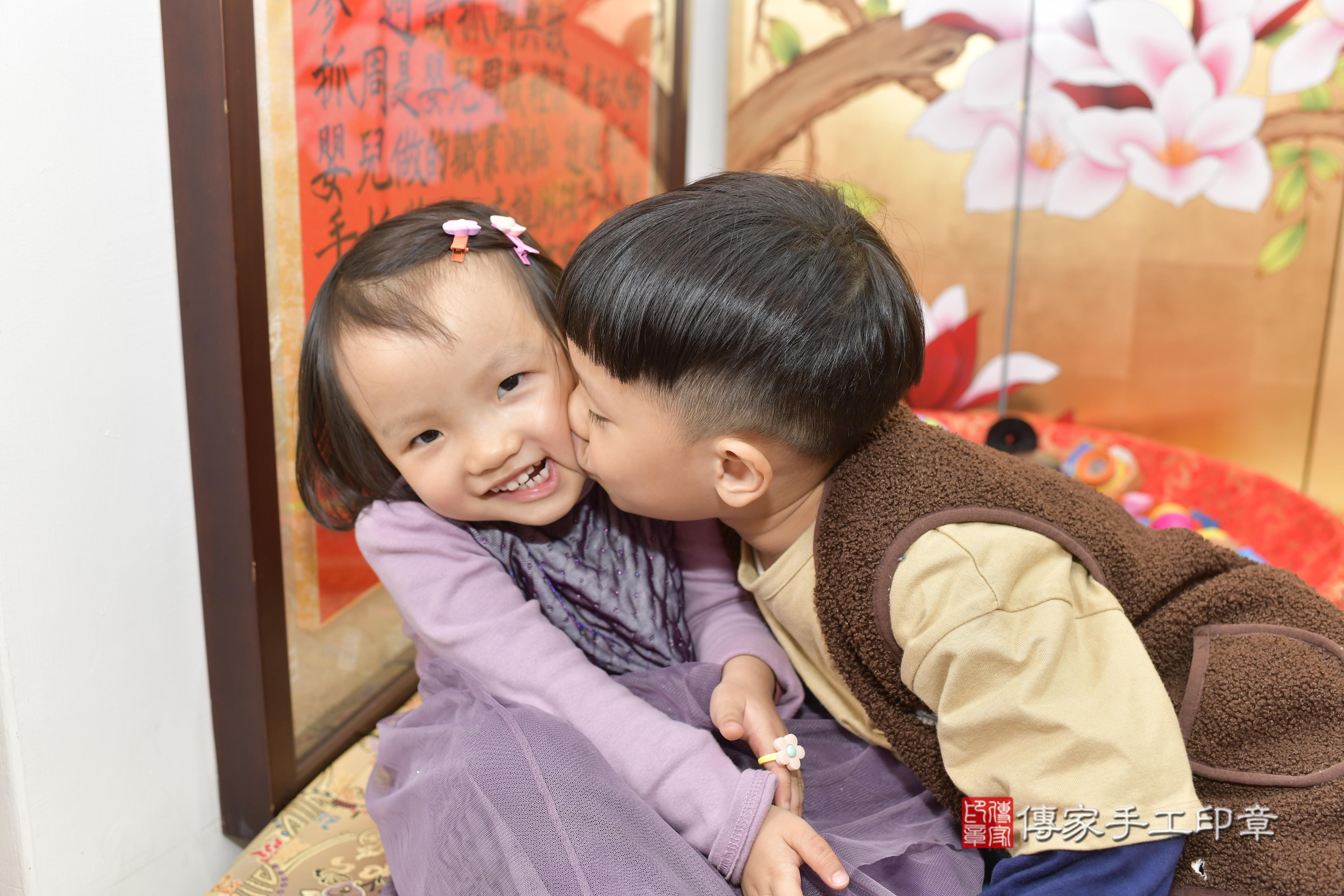 一家人一起穿著一套刺繡精美的紅色唐裝，笑容甜美，萌態十足。 這樣的傳統服飾，不僅為儀式增添了文化色彩，也讓這一天的紀念照片更加生動。
